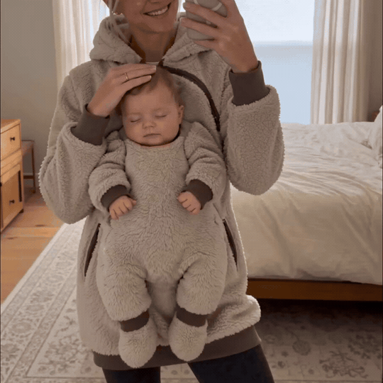 Eine Mama trägt ihr Baby nah bei sich im Kuschel-Hoodie